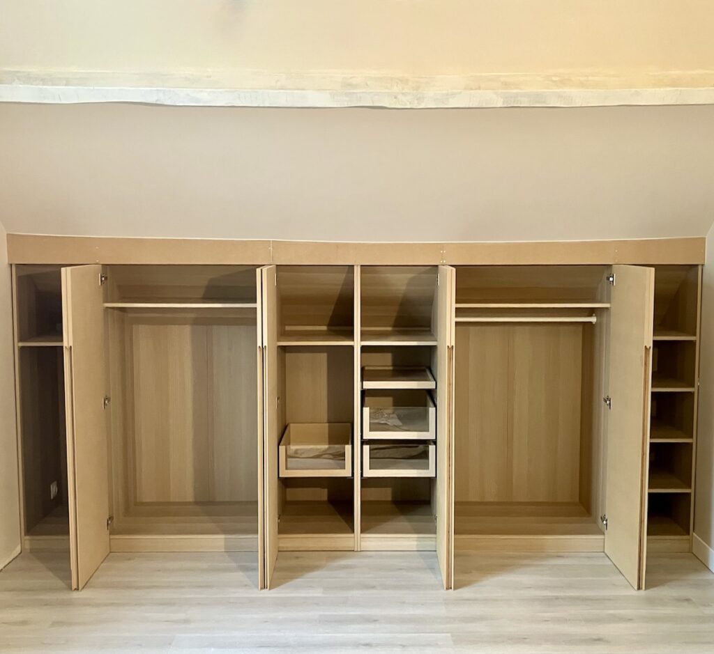 Aménagement sous combles avec dressings ouverts réalisés sur mesure pour optimiser les espaces sous pente.