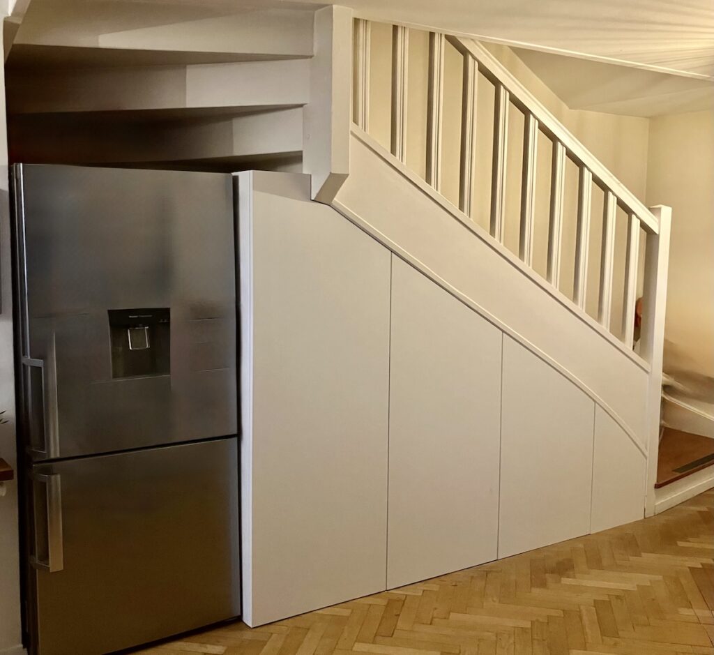 rangement sous escalier sur mesure comportant des rangements de cuisine intégrés, réalisés dans un appartement à Courbevoie dans les Hauts-de-Seine