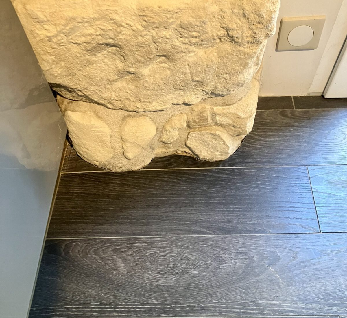 Ajustage minutieux du parquet autour d’un muret en pierre réalisé par votre menuisier situé à Courbevoie.