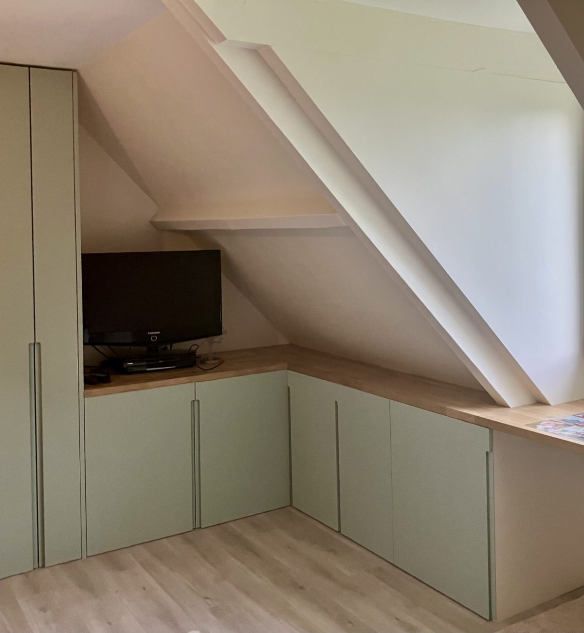 Vue d’ensemble d’une chambre sous combles avec dressing, placards sous pente et bureau en chêne sur mesure à Chatou.