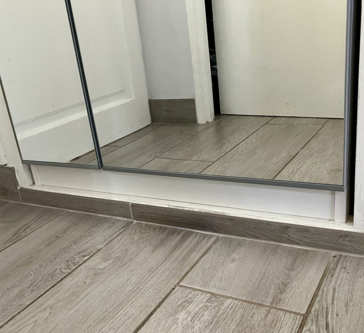 Détail de la plinthe en carrelage et des finitions manquantes sur le dressing encastré.