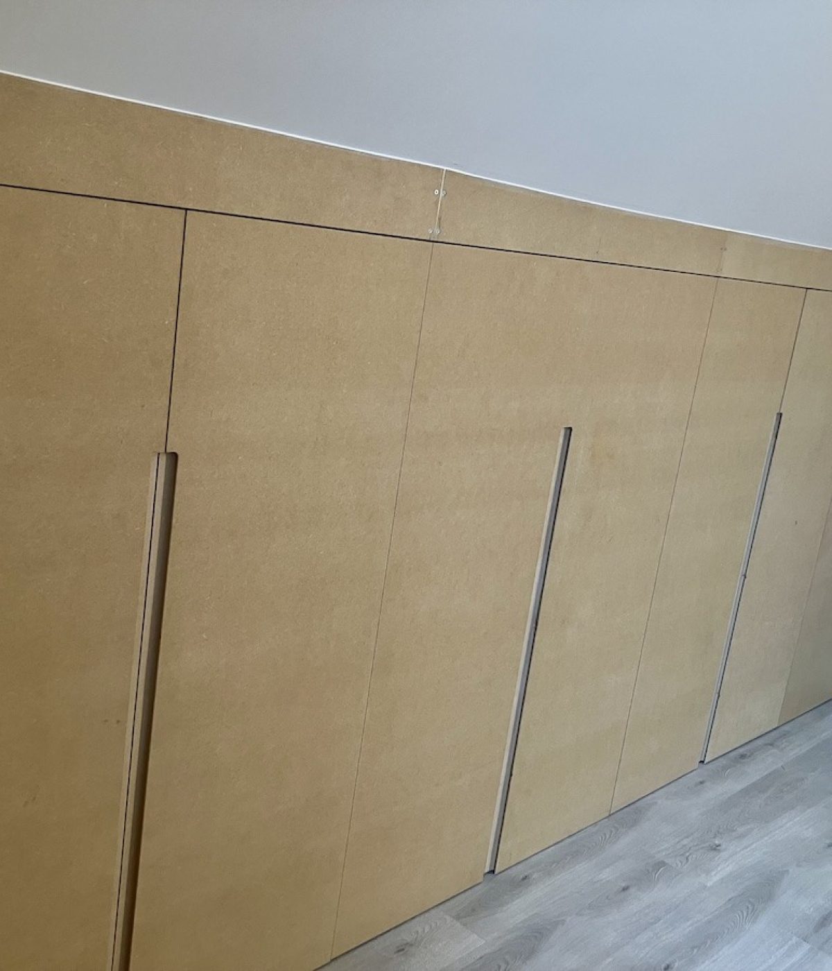 Portes sur mesure avec poignées intégrées ajustées aux rampants et aux irrégularités de la sous-pente.